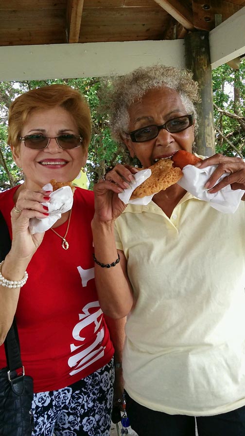 Norah Smith and Iris Corchado eating alcapurrias and bacalaitos at the picnic